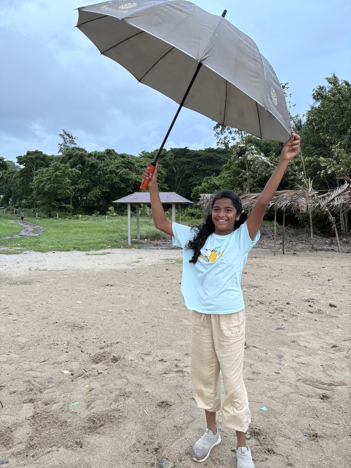 Anshika smiling outdoors with an umbrella